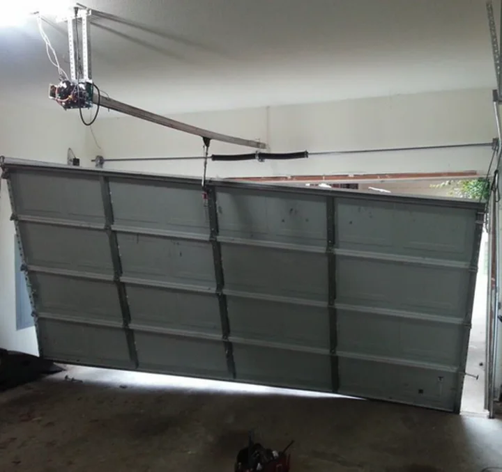 Sectional garage door hanging off the track inside a garage